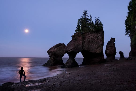 Luna y hombre en Hopewell Rocks en el Parque Nacional de Fundy